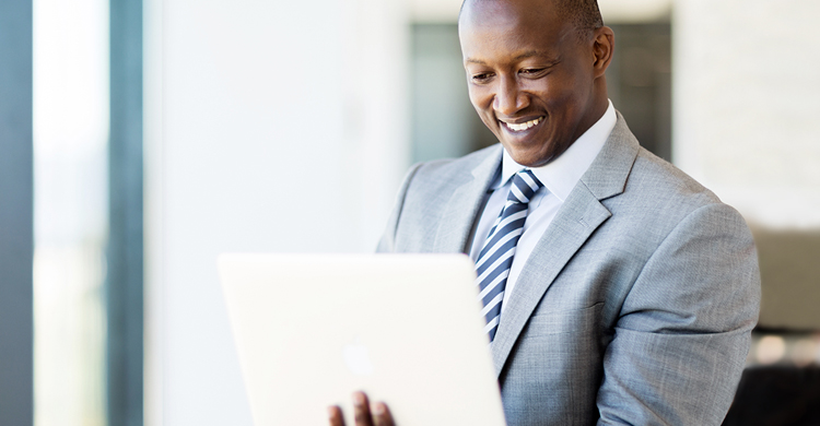 Smiling man in a suit looking at a laptop