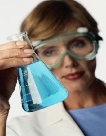 Female scientist examines a beaker of blue liquid.