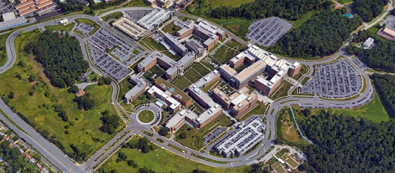 Arial view of a complex of buildings, surrounded by roads, parking lots, green space