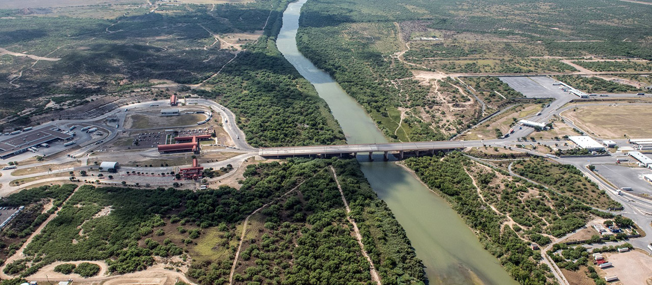 Aerial view of a bridge over a river, with bulding complexes and lots on each side