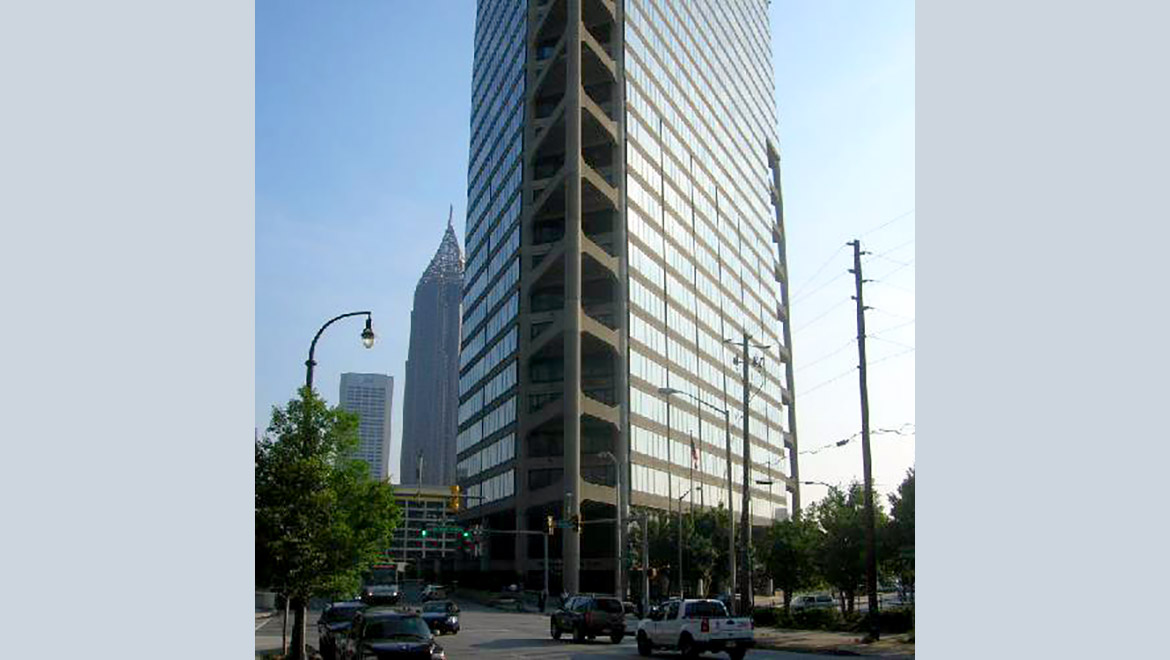 Multilevel cement and glass building which appears to have a triangular footprint in city surroundings