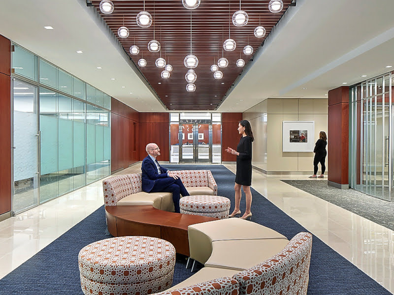 Two people having a conversation in a large, modern office building foyer