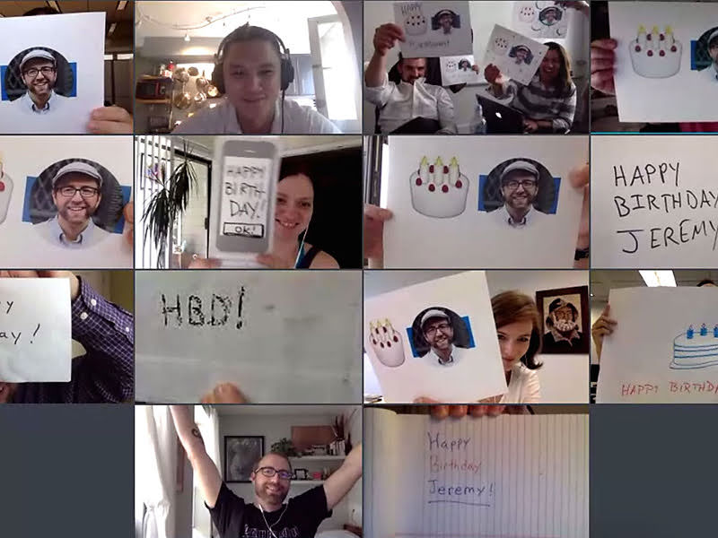 A screenshot of a virtual meeting with people holding signs with birthday cakes, birthday messages, and a picture of a person with a beard w