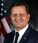 Portrait of Jeff Smith, who is wearing a dark jacket and tie, and a white shirt