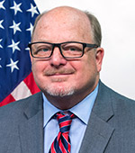 Headshot of Larry Allen. Larry wears a gray suit, blue shirt, and glasses.