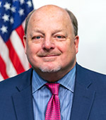 Headshot of Larry Allen. Larry wears a blue jacket, blue shirt, and dark pink tie.