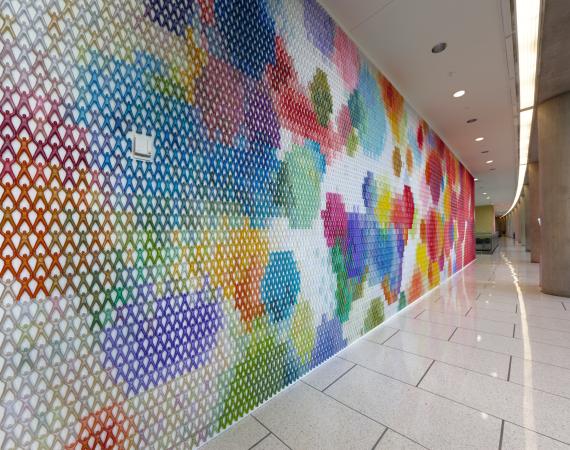 Installation of thousands of brightly colored plastic figures linked together on a wall