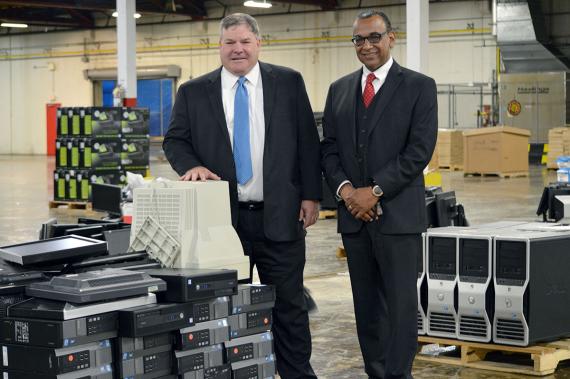 Two men in suits in a large warehouse standing amongst computer equipment