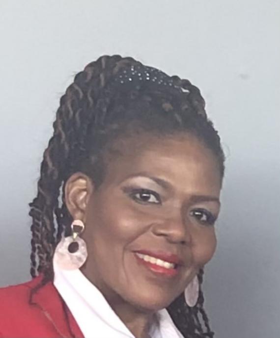 Photo of Bernita Gay smiling. She is wearing her hair up and has on a red jacket
