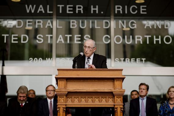 Medium shot of Judge Walter Rice speaking from the lectern to the crowd at the naming ceremony for the Walter H. Rice Federal Building and U.S. Courthouse, Dayton, Ohio.