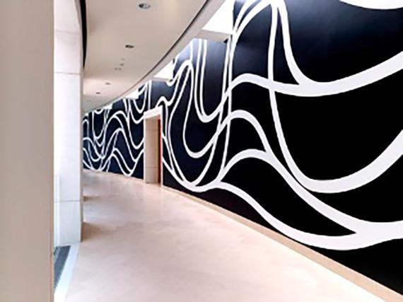 Black and white wall mural with abstract rope and loop shapes along the right side of an interior hallway