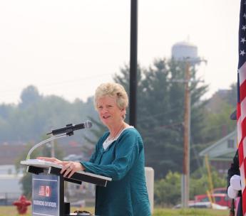 a woman in a green shirt stands at the podium