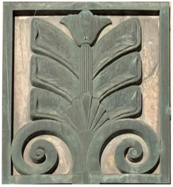 This image shows a bronze sculpture with a multifaceted design. The tops is a torch