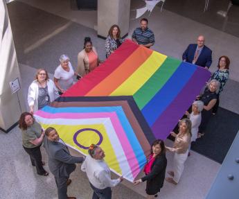 Region 8 employees hold open the Intersex-inclusive Progress Pride Flag in the lobby of the Regional Office Building prior to raising it over the Denver Federal Center.
