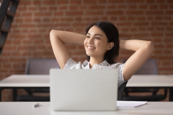 stock photo of woman relaxing at her desk behind a generic laptop