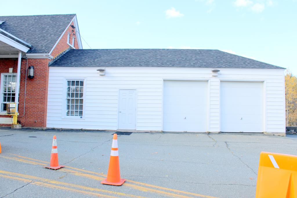 A white garage with orange traffic cones in front of it