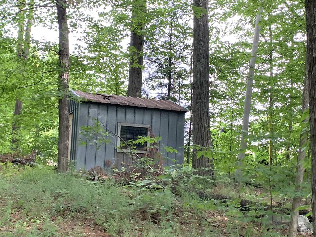 Small, gray-paneled, one-room, one-level structure with one window