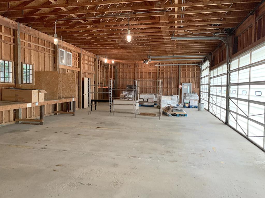 Large, garage-like interior with plywood and 2-by-4 walls and ceiling, and a cement floor, with 2 garage doors on the right