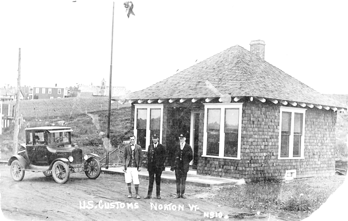 a photo of the original border station with a 1930s vehicle parked out front and three men standing in front of the building