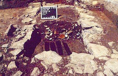 An old stone privy, marked by an archeological sign