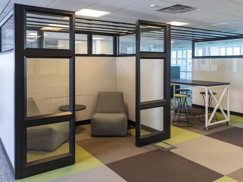 High cubicle room with two chairs next to a standing desk with three stools