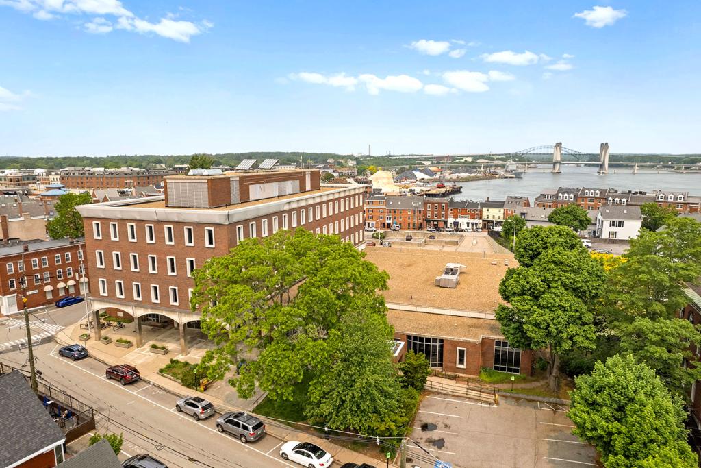 Aerial image of a four-story red brick building with a portico and a large one-story annex.