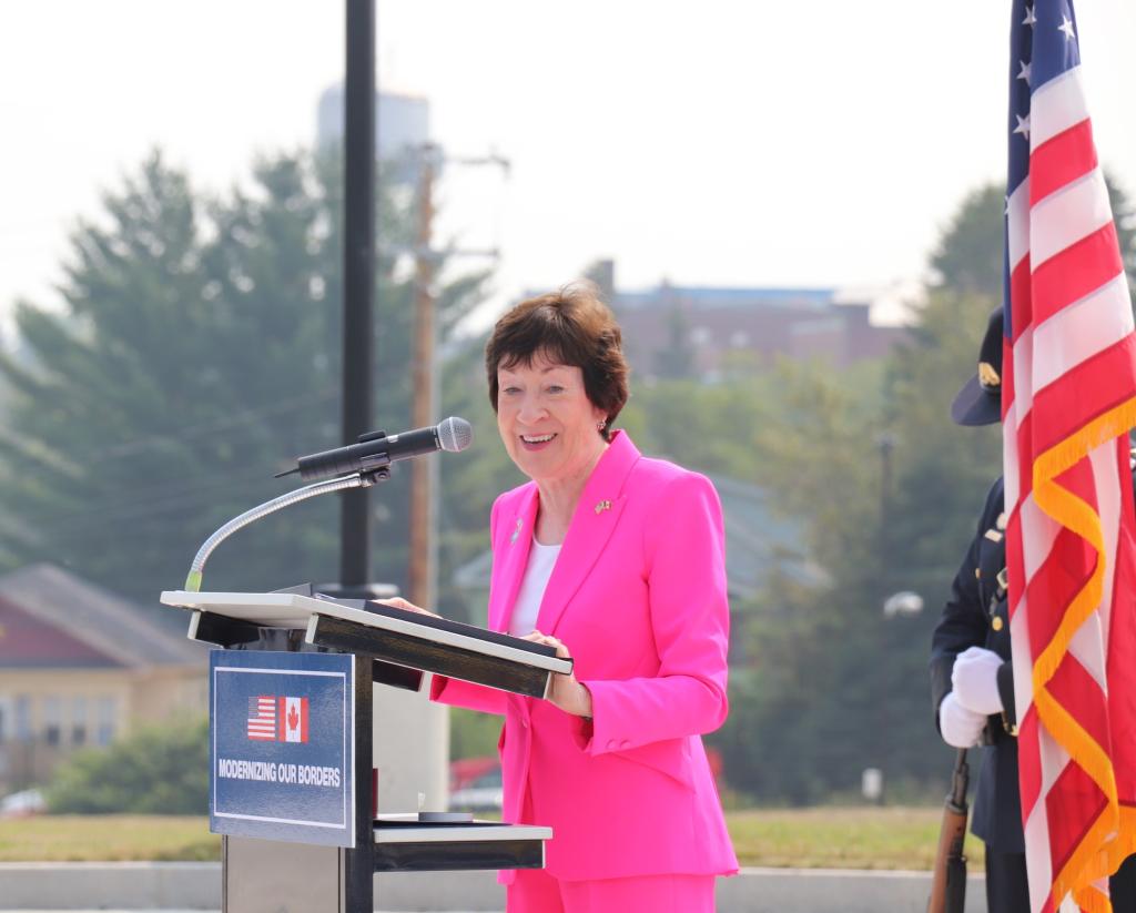 A woman in a pink suit stands at the podium