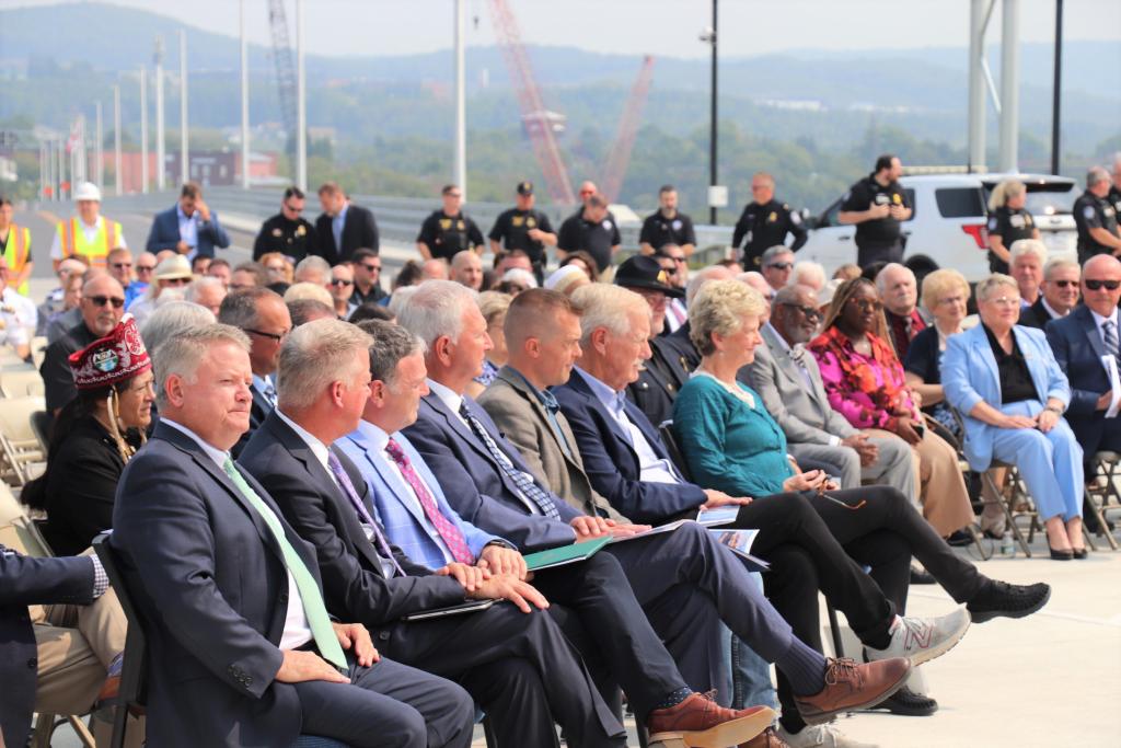 a group of people sit side by side in the front row of the ribbon cutting