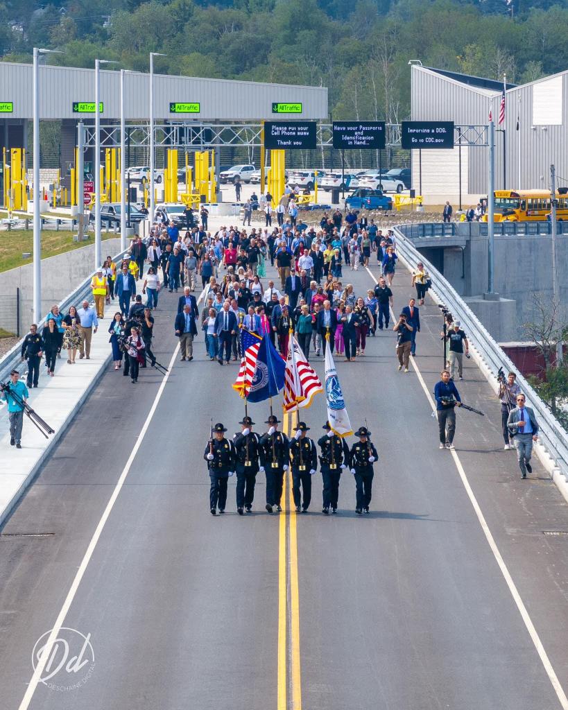 people with flags leading a crowd down the bridge