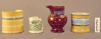 Irish Tenement and Saloon yellow ware mug; transfer-printed child's cup from the "Games and Pastimes" series (England, ca. 1820); luster ware creamer; and yellow ware (mocha) mug